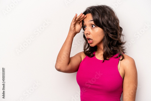 Young hispanic woman isolated on white background looking far away keeping hand on forehead.