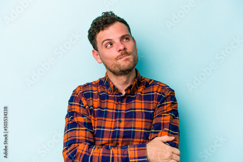 Young caucasian man isolated on blue background dreaming of achieving goals and purposes