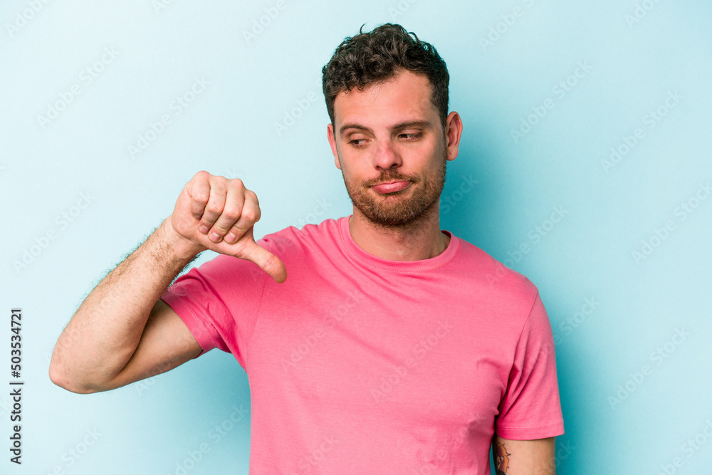 Young caucasian man isolated on blue background showing a dislike gesture, thumbs down. Disagreement concept. Young caucasian man isolated on blue background showing a dislike gesture, thumbs down. Disagreement concept.