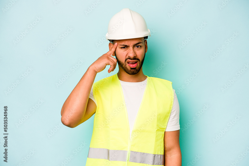 Young laborer hispanic man isolated on blue background showing a disappointment gesture with forefinger.