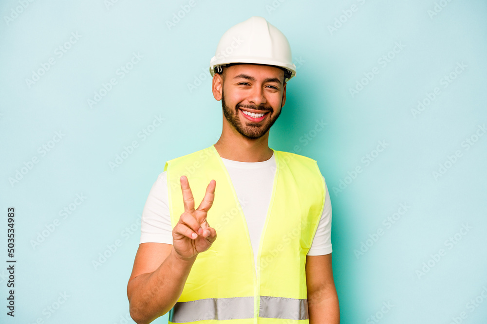 Young laborer hispanic man isolated on blue background showing number two with fingers.