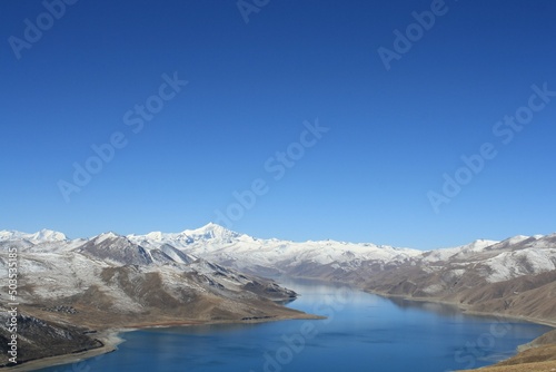 snow covered mountains Landscape of yamdrok tso lake surround with snow capped mountains and bright blue sky Tibet China. the freshwater lake in Tibet