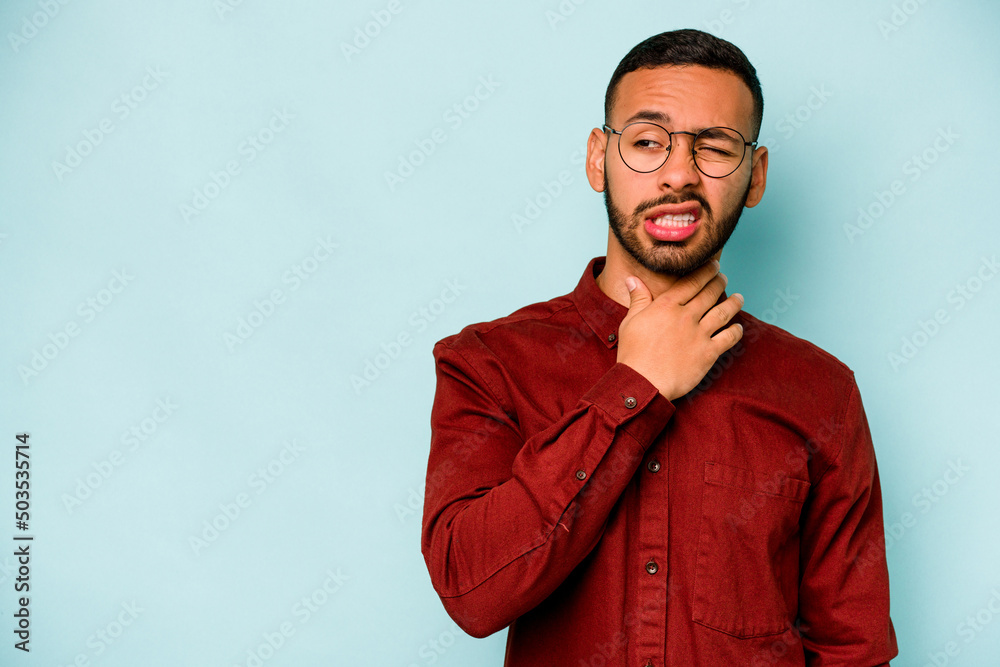 Young hispanic man isolated on blue background touching back of head, thinking and making a choice.