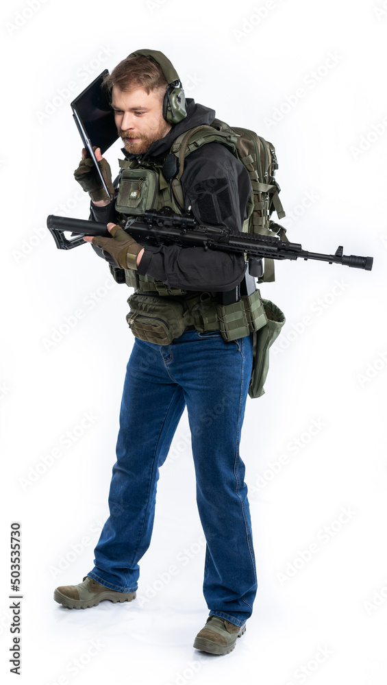 soldier, airsoft player in full gear works on a laptop in combat conditions. a man in headphones, a bulletproof vest, with a backpack and a belt, speaks, transmits information. White background. soldier, airsoft player in full gear works on a laptop in combat conditions. a man in headphones, a bulletproof vest, with a backpack and a belt, speaks, transmits information. White background.