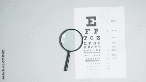 Checking, examination of vision. Magnifying glass with a sheet of text for an eye test on a gray background. Stop motion animation