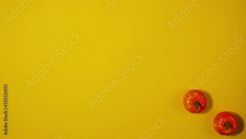 Halloween background with moving plastic decorative pumpkins on a yellow background. copyspace. Stop motion animation