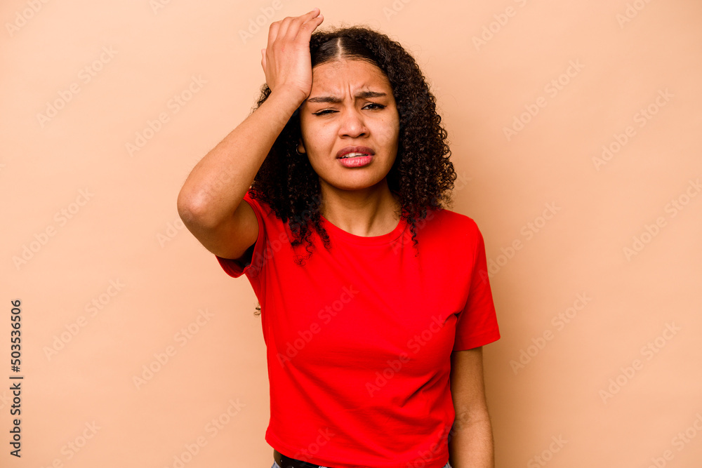 Young African American woman isolated on beige background forgetting something, slapping forehead with palm and closing eyes. Young African American woman isolated on beige background forgetting something, slapping forehead with palm and closing eyes.