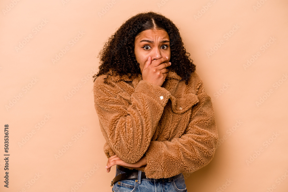 Young African American woman isolated on beige background scared and afraid. Young African American woman isolated on beige background scared and afraid.