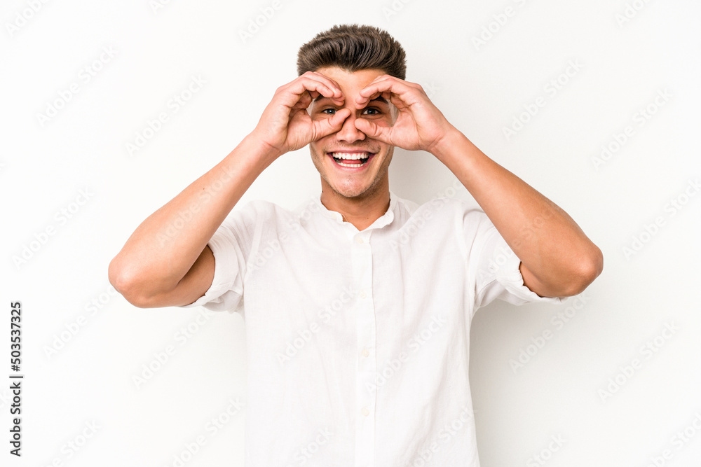 Young caucasian man isolated on white background showing okay sign over eyes Young caucasian man isolated on white background showing okay sign over eyes