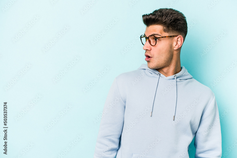 Young caucasian man isolated on blue background being shocked because of something she has seen. Young caucasian man isolated on blue background being shocked because of something she has seen.
