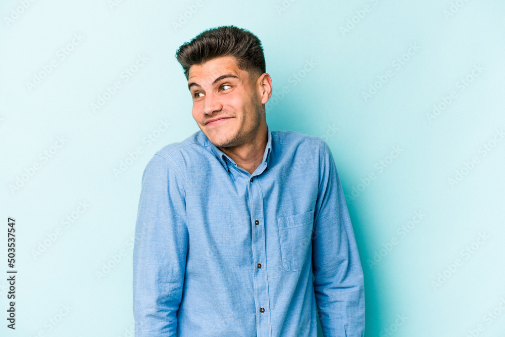 Young caucasian man isolated on blue background laughs and closes eyes, feels relaxed and happy. Young caucasian man isolated on blue background laughs and closes eyes, feels relaxed and happy.