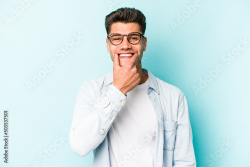 Young caucasian man isolated on blue background doubting between two options. © Asier