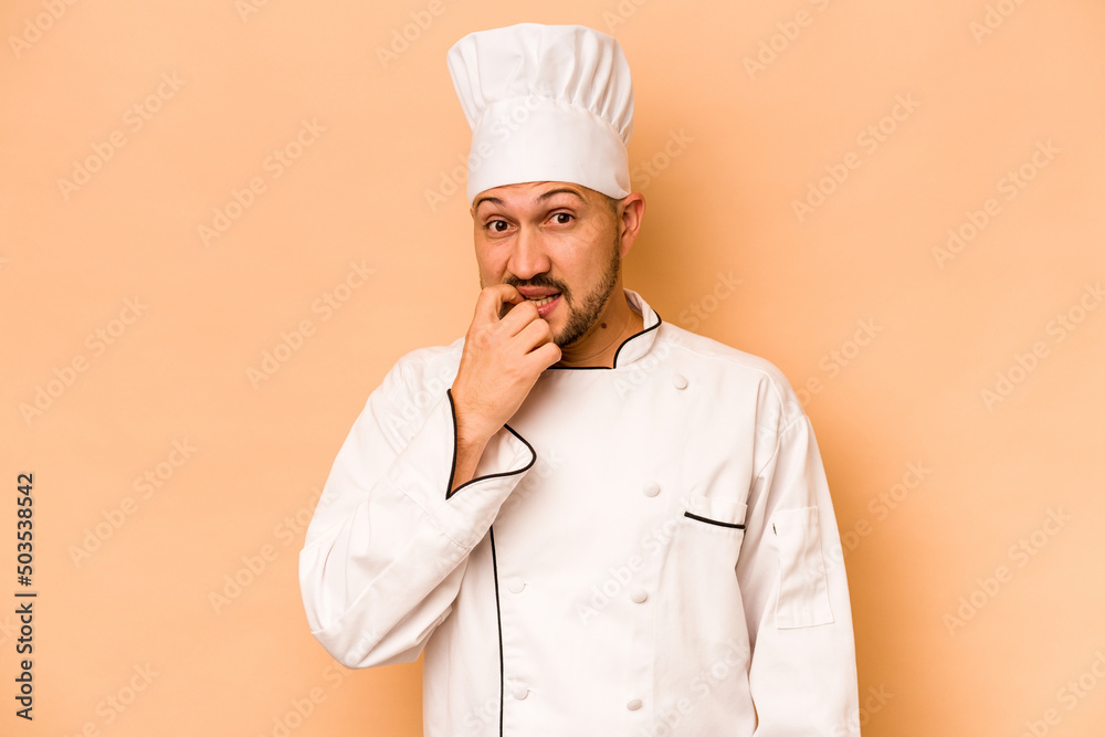 Hispanic chef man isolated on beige background biting fingernails, nervous and very anxious. Hispanic chef man isolated on beige background biting fingernails, nervous and very anxious.