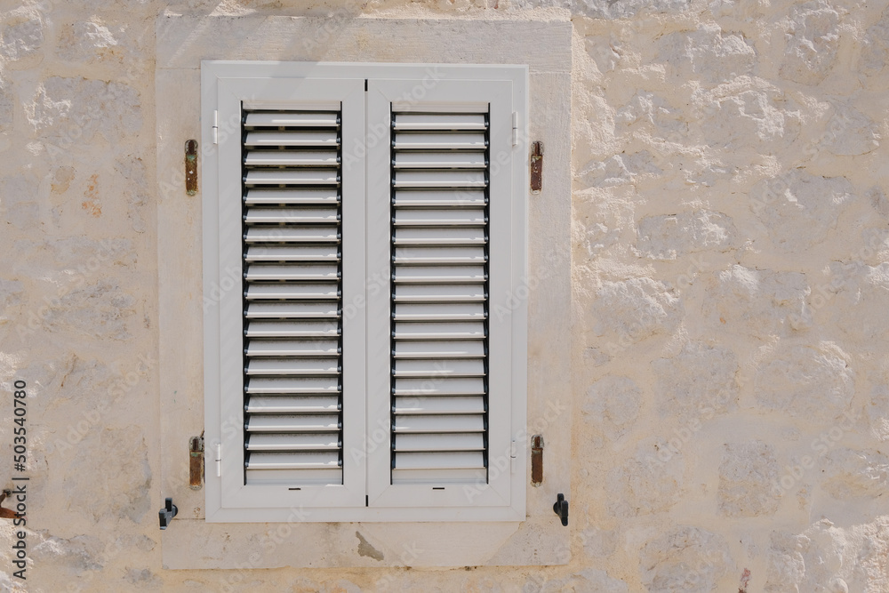 window with closed shutters on old white stone wall, renovation, reconstruction architecture, adriatic vintage travel card. closed possibilities concept. textured background