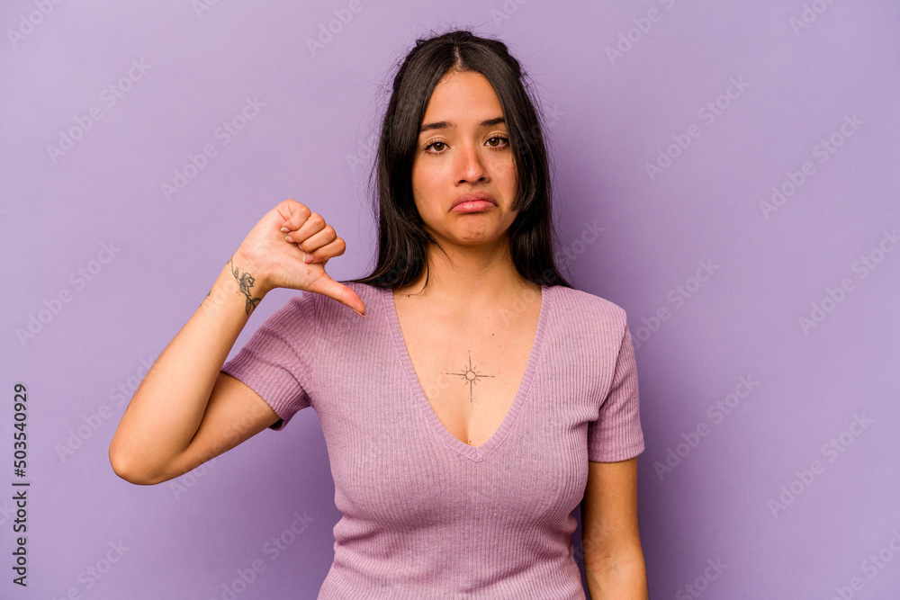 Young hispanic woman isolated on purple background showing a dislike gesture, thumbs down. Disagreement concept. Young hispanic woman isolated on purple background showing a dislike gesture, thumbs down. Disagreement concept.