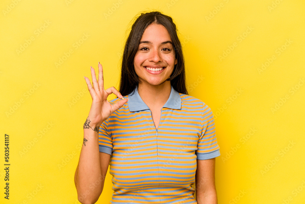 Young hispanic woman isolated on yellow background cheerful and confident showing ok gesture. Young hispanic woman isolated on yellow background cheerful and confident showing ok gesture.