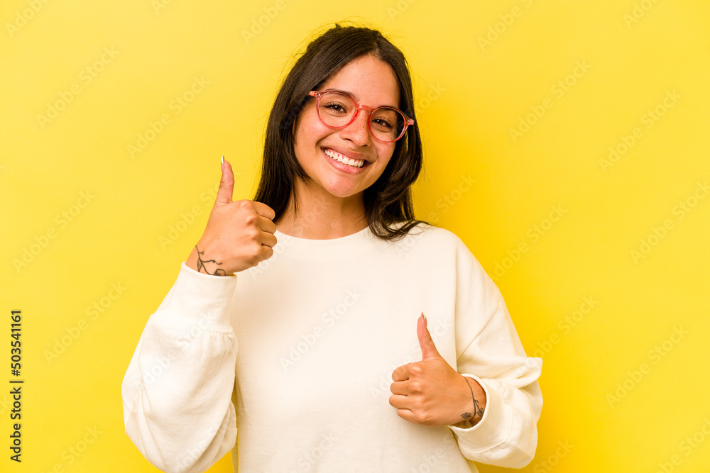 Young hispanic woman isolated on yellow background raising both thumbs up, smiling and confident. Young hispanic woman isolated on yellow background raising both thumbs up, smiling and confident.