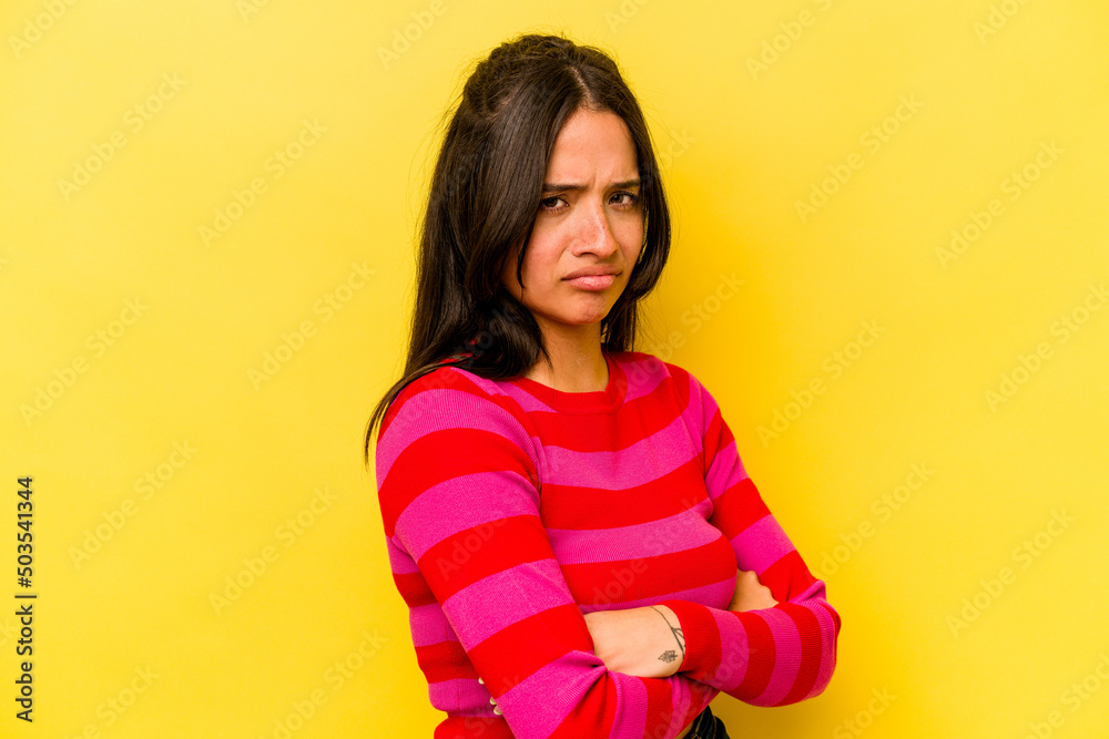 Young hispanic woman isolated on yellow background frowning face in displeasure, keeps arms folded. Young hispanic woman isolated on yellow background frowning face in displeasure, keeps arms folded.
