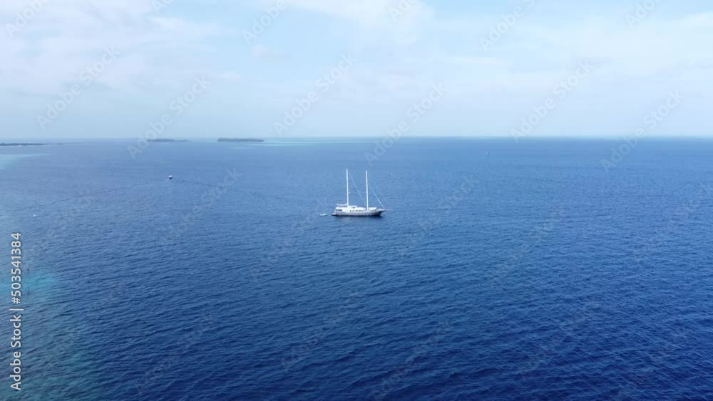 Big safari luxury yacht sailing on ocean in Maldives, tropical island on background. Concept of travel vacation and vessel trip. High quality 4k footage. Aerial view of beach Maldives. Big safari luxury yacht sailing on ocean in Maldives, tropical island on background. Concept of travel vacation and vessel trip. High quality 4k footage. Aerial view of beach Maldives.