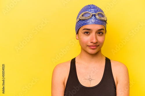 Young swimmer hispanic woman isolated on yellow background © Asier
