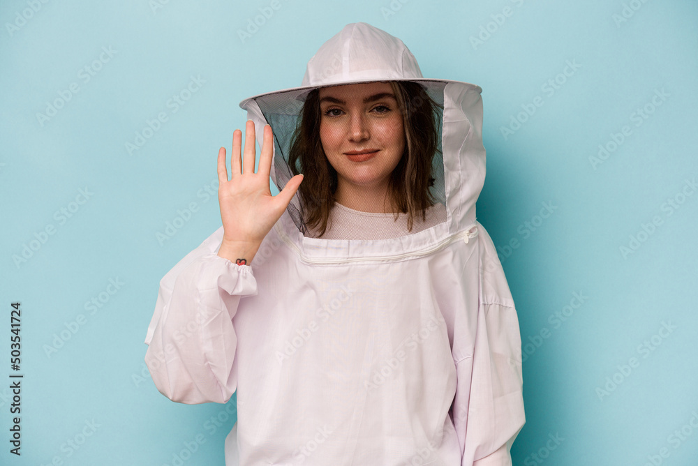 Young caucasian beekeeper woman isolated on blue background smiling cheerful showing number five with fingers. Young caucasian beekeeper woman isolated on blue background smiling cheerful showing number five with fingers.