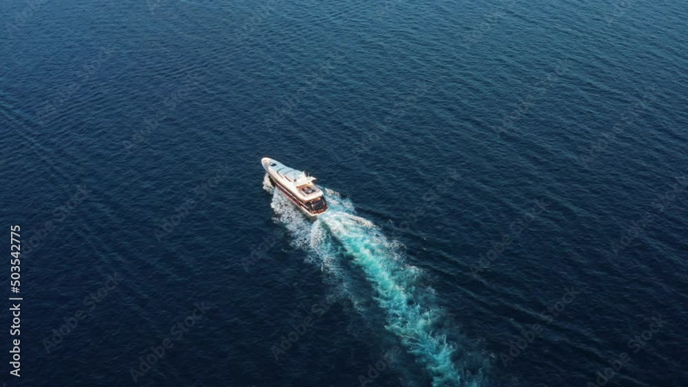 The lonely white yacht floats in the open dark blue sea. A tourist boat carries tourists to go diving. Yachtsman millionaire or billionaire resting in his free time The lonely white yacht floats in the open dark blue sea. A tourist boat carries tourists to go diving. Yachtsman millionaire or billionaire resting in his free time