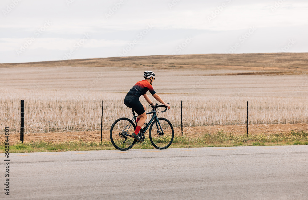Side view of professional female cyclist riding pro bike against agriculture field Side view of professional female cyclist riding pro bike against agriculture field
