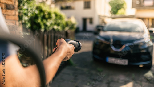 Hand hält Ladekabel das an Elektroauto angeschlossen wird photo