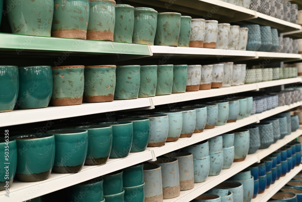 Fototapeta premium Rows of ceramic cups on display in a store, showcasing various shades of blue and green pottery.