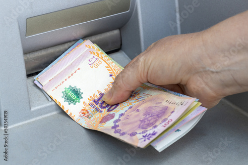 Woman Takes Argentinian Money From ATM, Economic Concept With Inflation And Rising Cost Of Living