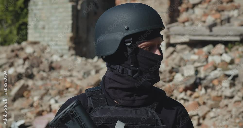 A Ukrainian soldier with a weapon against the background of a destroyed house.Close-up. A Ukrainian soldier with a weapon against the background of a destroyed house.Close-up.