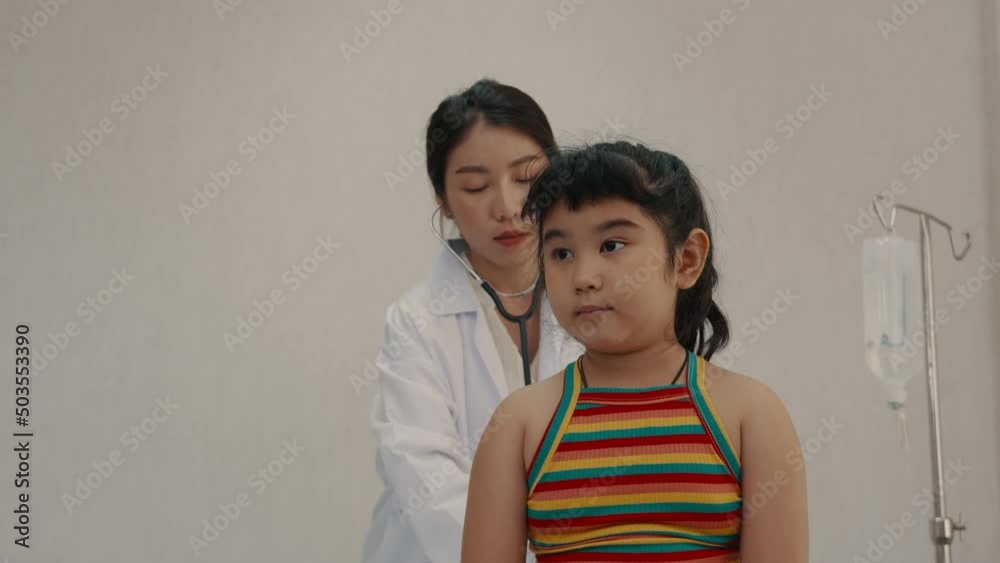 Doctor examining a cute smile girl with a stethoscope and write on clipboard in clinic room. Happy children check up her body and sit on bed hospital. Children medical insurance healthcare concept. Doctor examining a cute smile girl with a stethoscope and write on clipboard in clinic room. Happy children check up her body and sit on bed hospital. Children medical insurance healthcare concept.