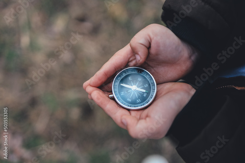 Navigation compass in hand. Travel and camping in forest. Finding path and direction