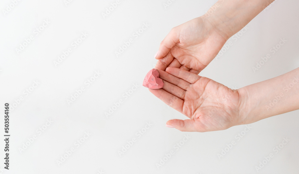 Handmade chocolate sweets above white background. Female hands holding candy pink heart