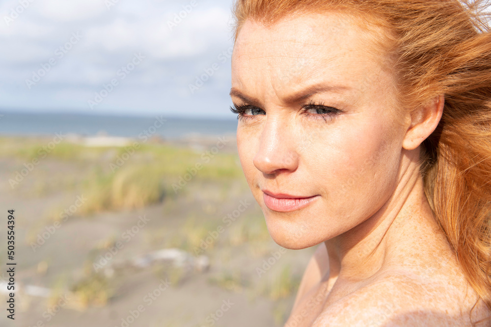 Redhead woman with freckles wearing dress at ocean beach. Redhead woman with freckles wearing dress at ocean beach.