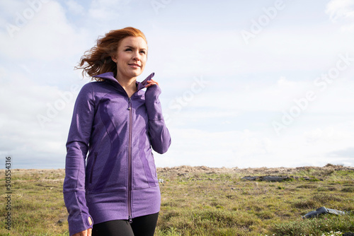 Redhead woman outside in countryside wearing purple workout jacket
