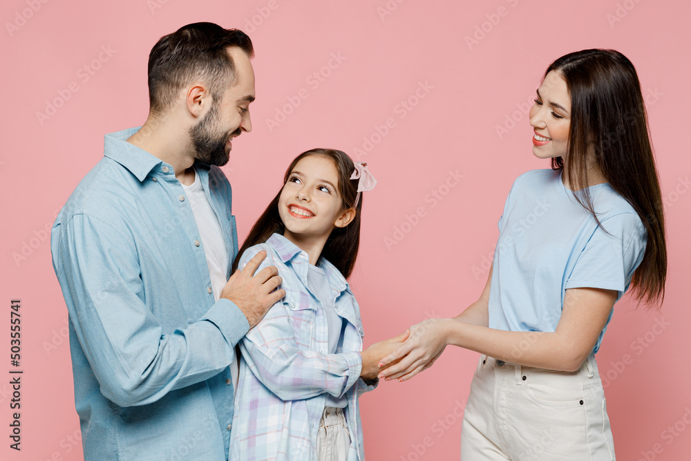SIde view young happy parents mom dad with child kid daughter teen girl in blue clothes shaking hands greeting isolated on plain pastel light pink background Family day parenthood childhood concept.