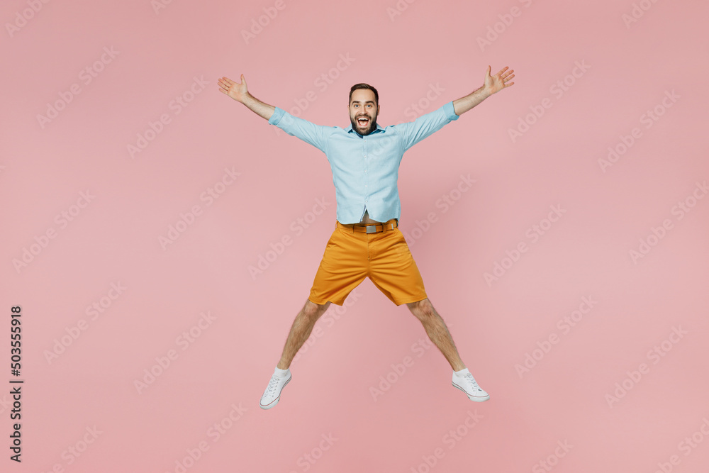 Full length young excited overjoyed winner fun happy caucasian man 20s wearing classic blue shirt jump high with outstratched hands legs isolated on plain pastel light pink background studio portrait