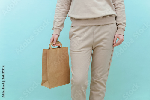 Caucasian woman holds craft package in her hand. Green background. © Iuliia Alekseeva