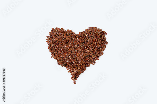Flax seeds in the shape of heart. White background.