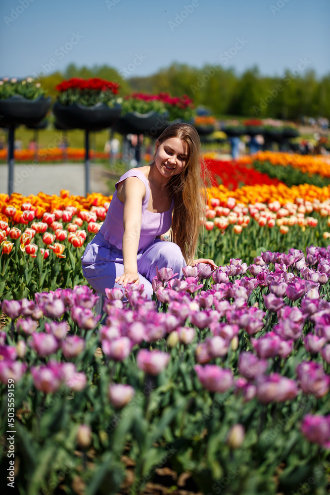 A young woman in a pink suit stands in a blooming field of tulips. Spring time A young woman in a pink suit stands in a blooming field of tulips. Spring time