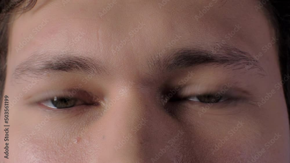 Extreme closeup confident male green gray eyes looking blinking with calmness emotion macro shot Extreme closeup confident male green gray eyes looking blinking with calmness emotion macro shot