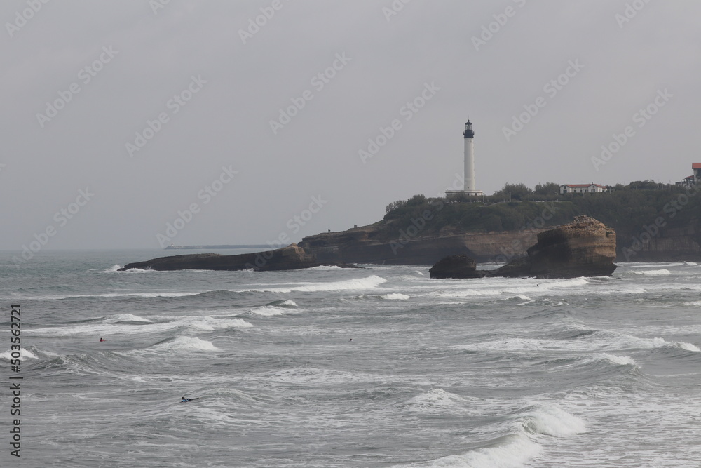 Biarritz coast beach and lighthouse with surfers