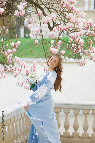 Amazing woman standing near a blooming magnolia, sweet girl in a blue dress. 