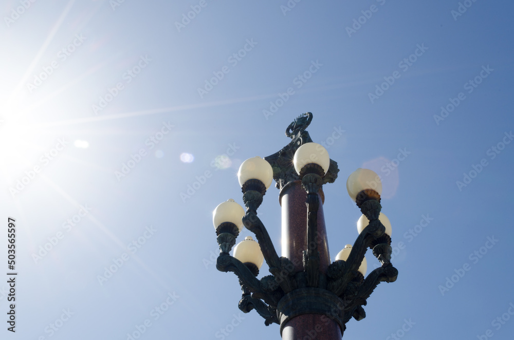 architectural details, a view of an Empire-style lamppost against a blue sky. white ceiling lights, granite pillar. Stalin's Empire. architectural details, a view of an Empire-style lamppost against a blue sky. white ceiling lights, granite pillar. Stalin's Empire.