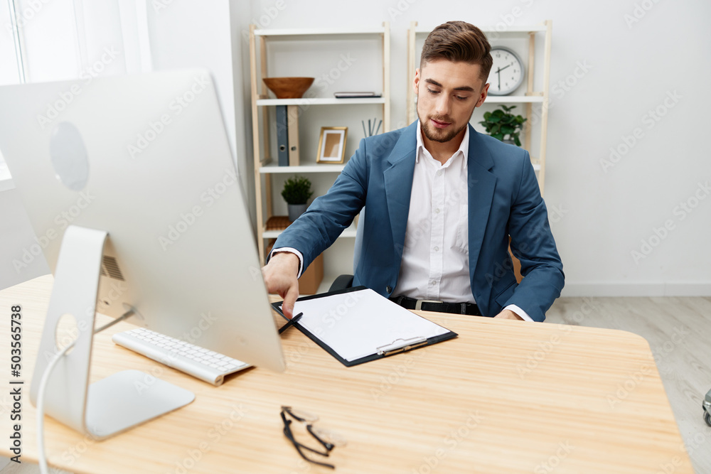 handsome businessman writes in documents at the desk in the office Gray background handsome businessman writes in documents at the desk in the office Gray background