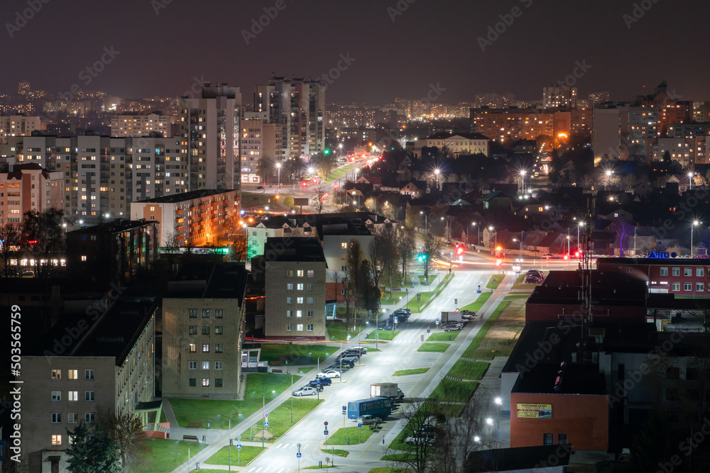 Night panorama of the city. Tall apartment buildings illuminated by night illumination. Top view of windows and roofs of houses