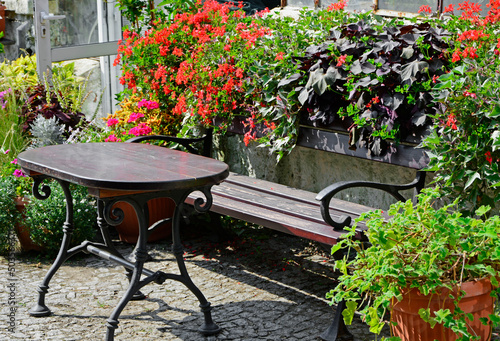 drewniany stół i ławka obok kolorowych kwiatów w doniczkach, wooden table and bench next to colorful flowers in pots, relaxation corner in the garden