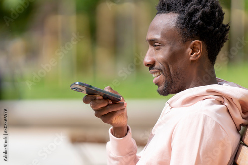 Man sending an audio message with smartphone in the park