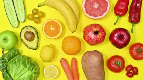 Organic healthy fruits and vegetables in vivid colors move on yellow background. Food pattern. Stop motion flat lay